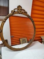 Full view of antique round mirror showing the ornate gilt wood frame and surface age wear.