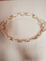 Full view of the oval serving platter showing overall shape, floral decorations on rim and gold detailing on edges.