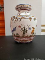 Front view of a handpainted ceramic vase with bird and rabbit motifs on white background and decorative borders in yellow and blue.