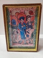 Front view of vintage wooden music box with glass front showing colorful drawing of children and balloons with 'Happy Folks' text.