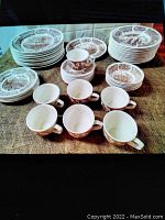 Full set with plates, bowls, cups, and saucers shown on burlap surface.