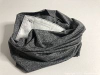 Gray neck gaiter folded with a PM2.5 filter partially visible inside.