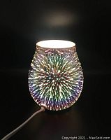 Front view of the electric wax melt warmer lit up, showing the 3D fireworks glass pattern.