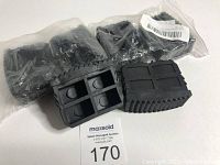 Photo of 6 black rubber replacement slip proof ladder feet covers in plastic bags with one out for display showing the textured grip surface and hollow design.