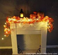 String lights with 40 warm white maple leaf LED bulbs displayed draped over a fireplace mantle decorated with additional fall pumpkins and decorations.