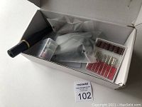 White box containing a matte black nail drill pen, various metal and sanding drill bits in plastic cases, and USB cable in plastic bag.