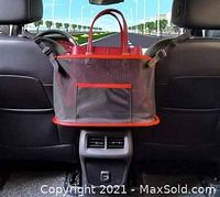 Mesh car organizer hanging on car backseat showing red trim, large storage compartment, and adjustable black straps with clips.