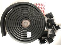 Top view of the rolled black foam edge guard and eight corner bumpers beside it, showing length and pieces included.