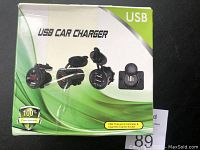 Front view of the original box showing images of the USB car charger with voltmeter and cigarette lighter socket, with 100% warranty displayed.