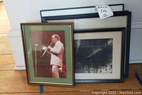Six pieces of framed wall art leaning against a wall and floor, including a color photograph and black and white prints.
