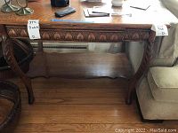 Full view of the wooden table top and front carved apron, showing detailed wooden carvings and wear.