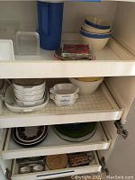 Shelf with assorted dishes: CorningWare casserole dishes, bowls, plates, glass containers