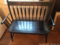 Front view of the vintage dark wood bench showing contoured seat, armrests and painted floral design on the backrest.