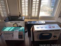 Photo showing the three boxed or partially boxed items: Garmin StreetPilot c330 GPS, Multiband Portable Radio, and Hand Crank / Solar Radio in box.