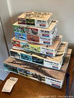 Stack of six Monogram model airplane kits: Boeing F4B-4, Tiger Shark, Mustang P-51D, Airacobra P-39, Messerschmitt Me 262, and B-26 Marauder.