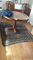 Rug under round wooden table showing overall size and pattern.