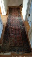 Full length photo of the worn runner rug showing geometric floral pattern and overall color tone.
