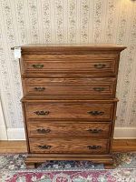 Front view of the upright dresser showing five drawers with ornate metal handles and solid oak finish.