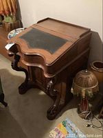 Front left angle view of carved wood desk showing claw feet and leather top