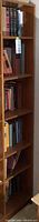 Overview of the smaller side of the bookcase showing all four shelves with assorted hardcover books