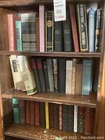 Bookshelf with assorted books including vintage and modern editions, various colors and sizes.