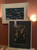 Overview of both cloisonné artworks in white frames hanging on wall