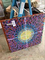 Full view of the colorful abstract painting showing a central light burst with surrounding purple, blue, red, and green brushstrokes.
