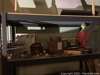 Overview of shelf showing decorative doll, stain remover kit box, nested wooden bowls, assorted coins and keys.
