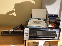 Photo of Epson XP-410 printer with papers and startup disk on top, next to a paper cutter.