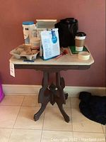 Front angle view of the marble top wooden side table with various objects on top.