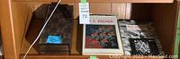 Shelf display showing closed wooden chessboard box with MC Escher design alongside three M.C. Escher books.