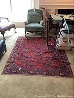 Full view of the oriental rug placed on a carpeted floor with furniture around it, showing the overall design and color.