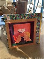 Two original framed paintings on Masonite showing two profile faces with a patterned border and an abstract shape above. Both paintings measure 28 x 28 inches and signed by artist Wilfred '012.