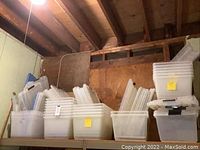 Multiple plastic storage bins and lids arranged and stacked on shelves. Clear and white semi-transparent plastic, varied sizes.
