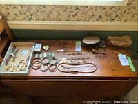 Wide shot of wooden surface showing assorted costume jewelry, belts, bangles, jewelry boxes and tins