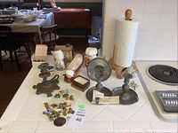Table display showing bronze animal statues, sailor men salt & pepper shakers, Kingston-style Metropolitan Museum candlesticks, a barometer, and various small collectible items.