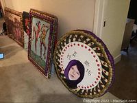 Photo of three unique art pieces by Wilfred Sarr with custom colorful foam frames leaning against a wall.