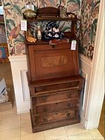 Front view of closed desk showing fold-down panel with burl wood inlay, upper shelf and four lower drawers