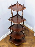 Full view of wooden 5-tier corner display shelf against white wall and hardwood floor
