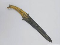 Full view of the dagger showing curved blade with horsehead handle painted gold.