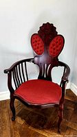 Front view of the Victorian armchair showing red button-tufted upholstery on backrest and seat, with carved wooden frame and cabriole legs.