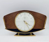 Front view of clock showing wooden case, brass trim, white dial, and hands