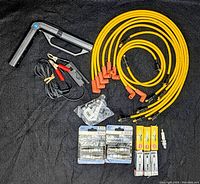Lot laid out on dark fabric showing timing light, spark plug wires, spark plugs, and connectors