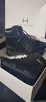 Halston black lace-up boots displayed in their original box with branding visible on lid.