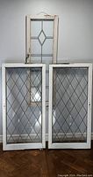 Three vintage leadlight windows including two lattice pattern casement windows and one window with central diamond design, showing paint distress and glass damage.