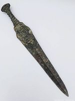 Full view of the old cutting tool showing the entire blade and handle with patina and corrosion.