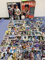Lot including 1954 Dell Baseball Annual, 1988 Street & Smith's Baseball magazine, Franklin Official League baseball, and extensive baseball trading cards spread out on a table.
