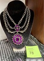 Front full view of the heavy triple strand necklace on a black velvet display showing the intricate stone settings.