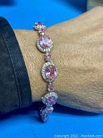 Bracelet worn on wrist showing pink oval stones surrounded by white simulated diamonds in sterling silver setting.