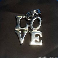 Front view of polished sterling silver LOVE charm pendant with block style letters L, O, V, E.